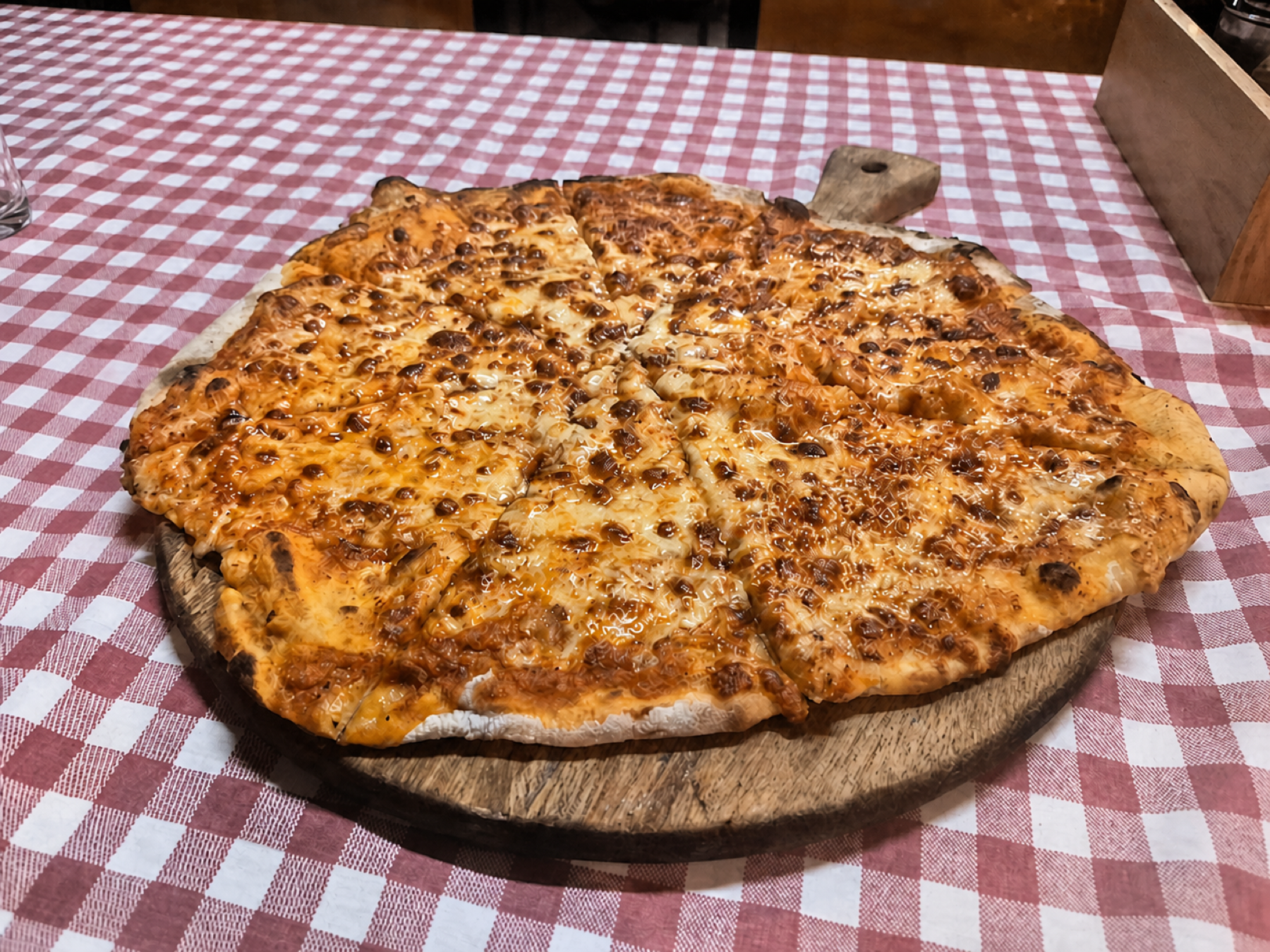 Casa Mia cheese pizza on a red checked tablecloth