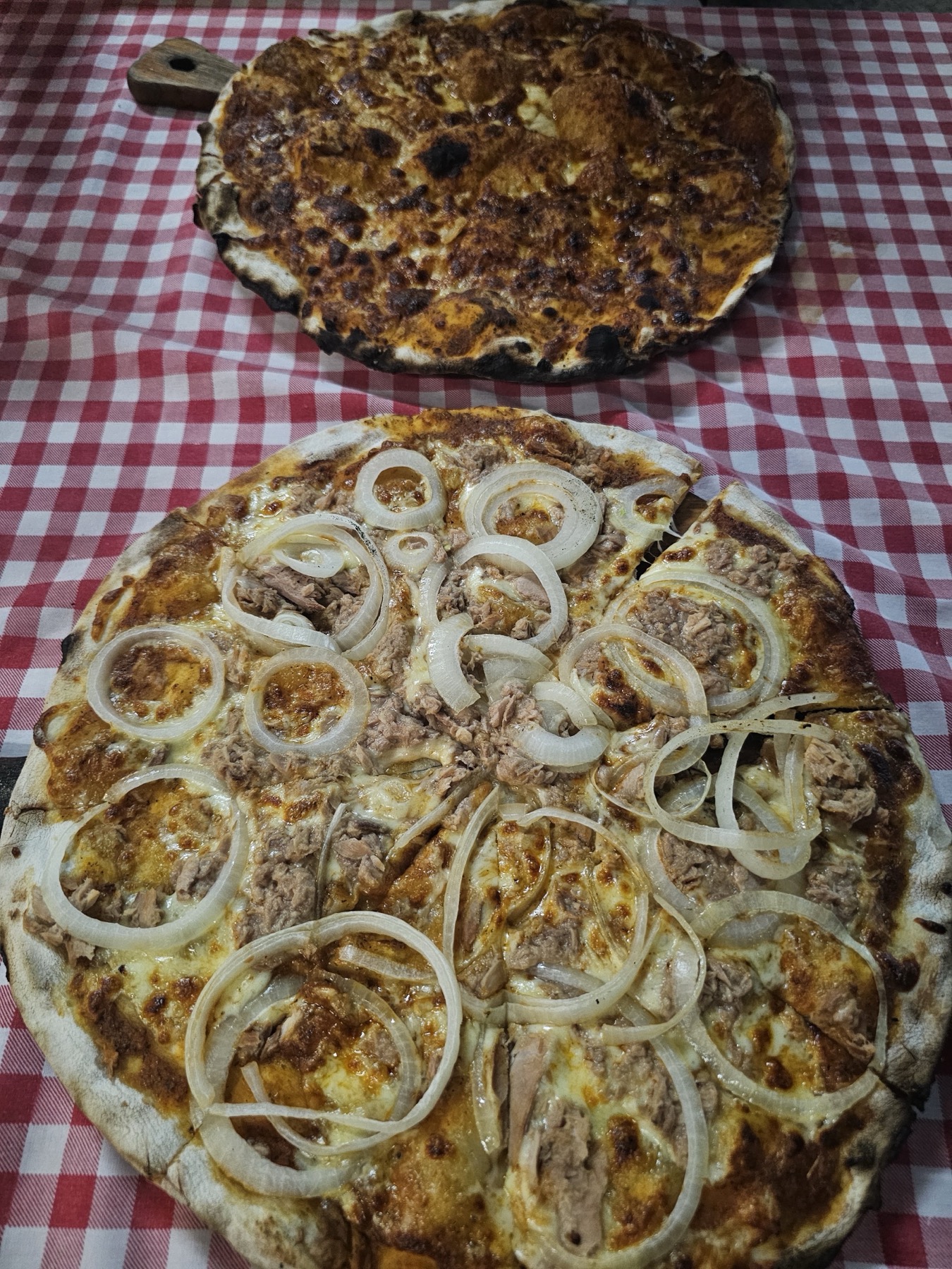 Tuna and onion pizza on a red checked tablecloth